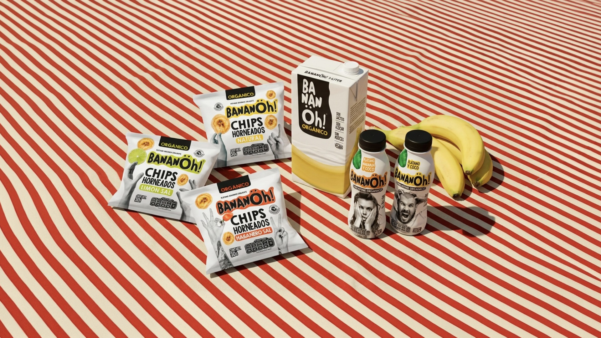 BananÖh! full product range: Chips Horneados bags in Natural, Limón-Sal, and Habanero-Sal, a BananÖh! Orgánico milk-carton pack, and two BananÖh! Smoothie Orgánico bottles in Plátano Naranja and Coco, styled with real bananas