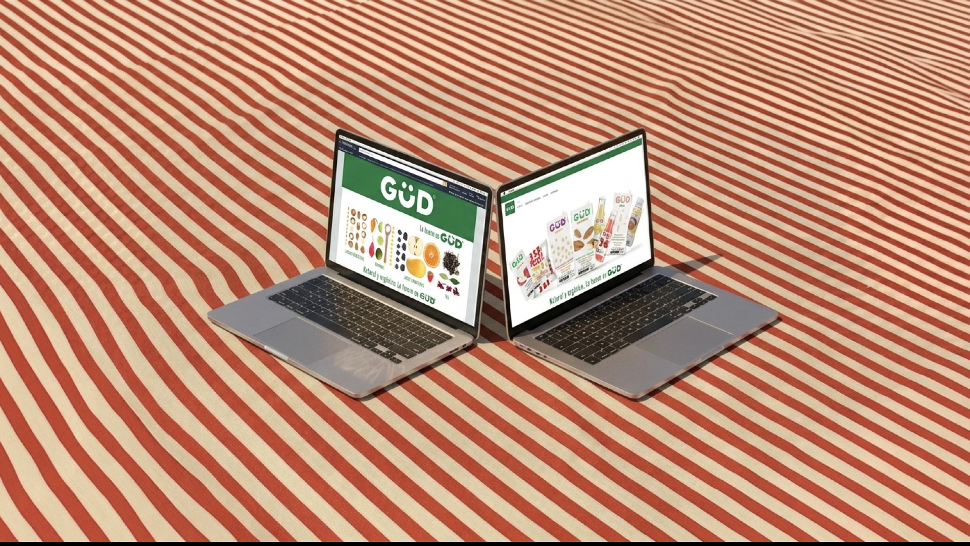 Two laptops side by side showing the GÜD website — the homepage hero and the full product grid, Natural y orgánico