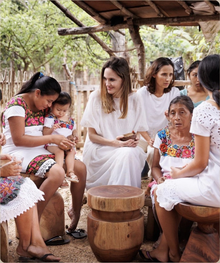 Angelina Jolie seated with Mayan artisan women and a child, part of the Bee School community visit