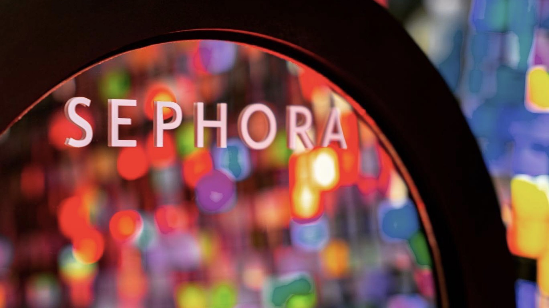 Macro shot of the circular Sephora sign at the Beauty Fair activation, seen through a ring of blurred colored light