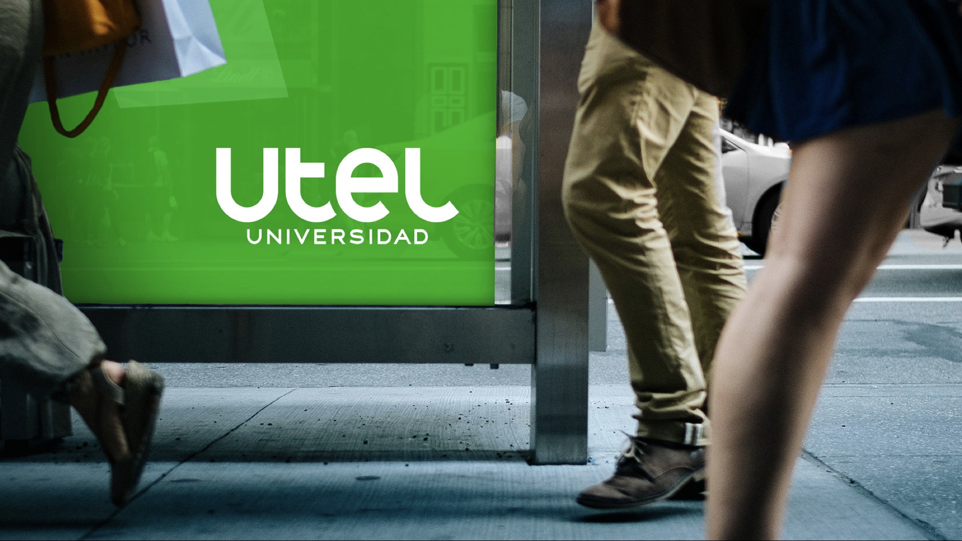 UTEL Universidad bus shelter billboard at street level, pedestrians walking past